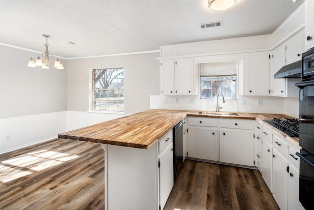 kitchen with wood counters, sink, white cabinets, hanging light fixtures, and black appliances