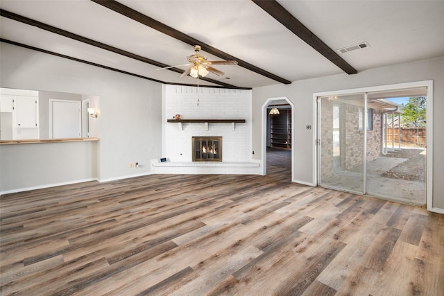 unfurnished living room featuring vaulted ceiling with beams, wood-type flooring, a fireplace, and ceiling fan