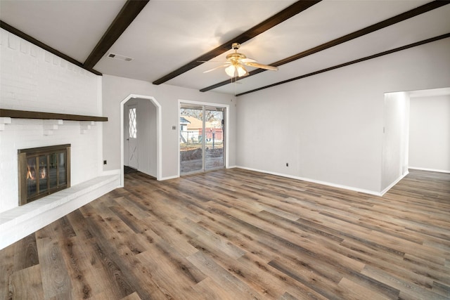 unfurnished living room featuring dark hardwood / wood-style flooring, ceiling fan, a fireplace, and beam ceiling