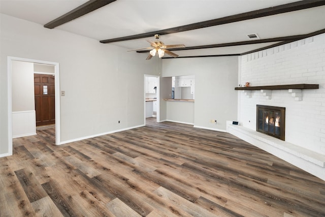 unfurnished living room featuring dark wood-type flooring, a brick fireplace, and beamed ceiling