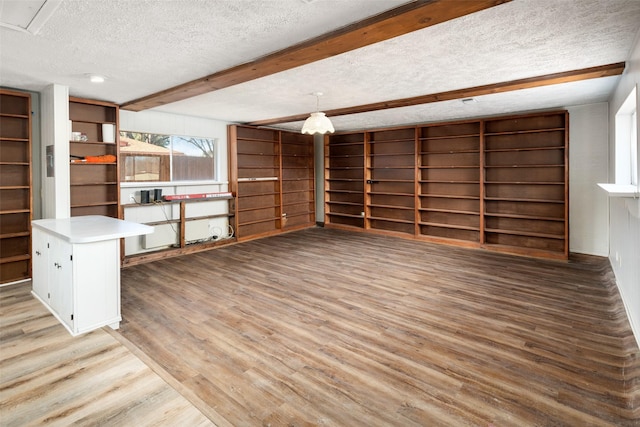 interior space featuring beamed ceiling, a textured ceiling, and light wood-type flooring