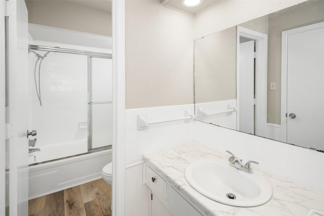 full bathroom with bath / shower combo with glass door, hardwood / wood-style floors, vanity, and toilet