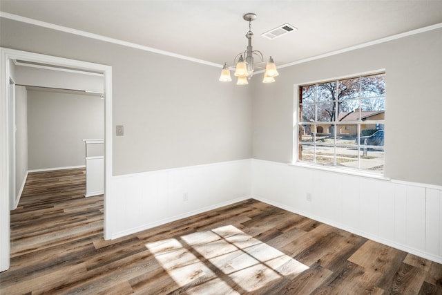 unfurnished dining area featuring an inviting chandelier, ornamental molding, and dark hardwood / wood-style flooring