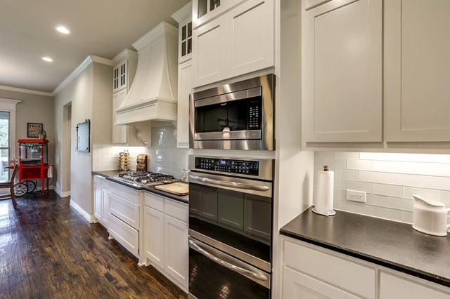 kitchen with premium range hood, appliances with stainless steel finishes, dark hardwood / wood-style floors, white cabinets, and ornamental molding