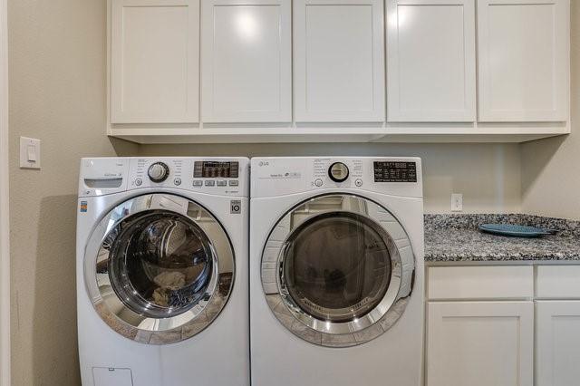 washroom featuring cabinets and washer and clothes dryer