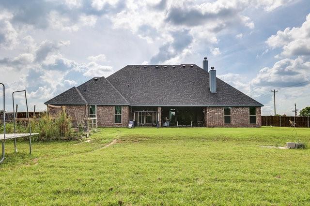 back of house featuring a trampoline and a lawn