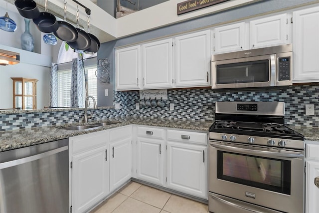 kitchen with light tile patterned floors, tasteful backsplash, appliances with stainless steel finishes, stone counters, and a sink