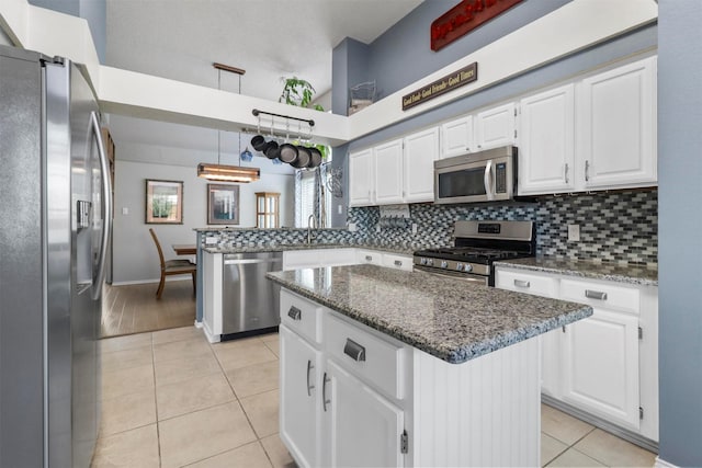 kitchen featuring light tile patterned floors, white cabinets, decorative backsplash, a peninsula, and stainless steel appliances