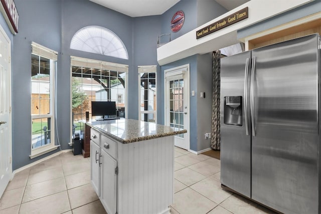 kitchen featuring white cabinets, a kitchen island, stainless steel refrigerator with ice dispenser, and light tile patterned floors