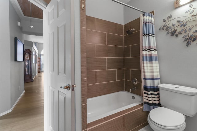 bathroom with tiled shower / bath combo, baseboards, toilet, and wood finished floors