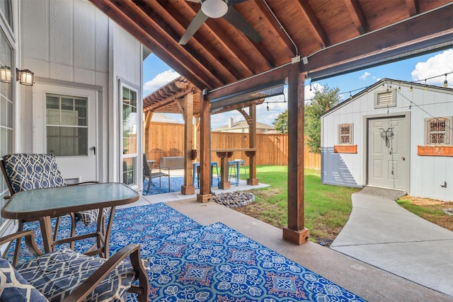 view of patio with a ceiling fan, outdoor dining space, fence, and an outdoor structure