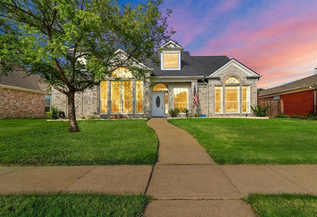 view of front of property with brick siding, a lawn, and a shingled roof