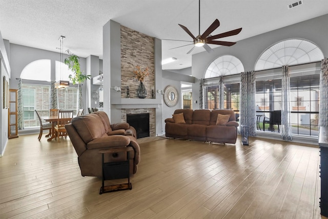 living area featuring a fireplace, wood finished floors, visible vents, and a healthy amount of sunlight