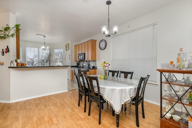 dining room featuring sink, an inviting chandelier, and light hardwood / wood-style floors