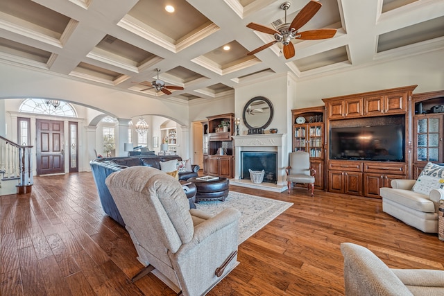 living room with dark hardwood / wood-style flooring, beam ceiling, ceiling fan, and a high ceiling