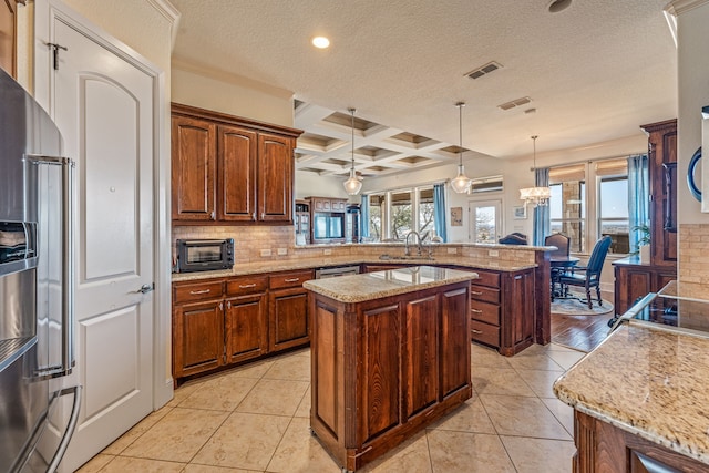 kitchen with appliances with stainless steel finishes, a kitchen island, backsplash, hanging light fixtures, and kitchen peninsula