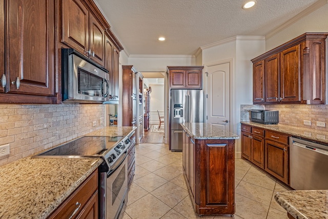 kitchen featuring a kitchen island, ornamental molding, light tile patterned floors, light stone counters, and stainless steel appliances