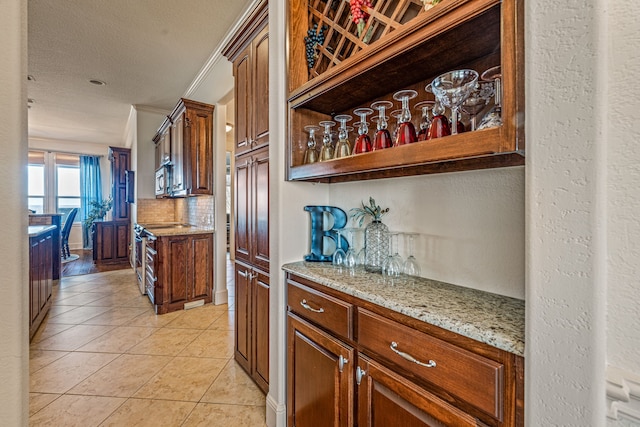 bar featuring crown molding, a textured ceiling, light tile patterned floors, light stone countertops, and decorative backsplash