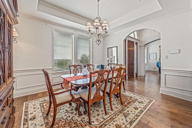 dining space featuring an inviting chandelier, ornamental molding, dark hardwood / wood-style flooring, and a raised ceiling