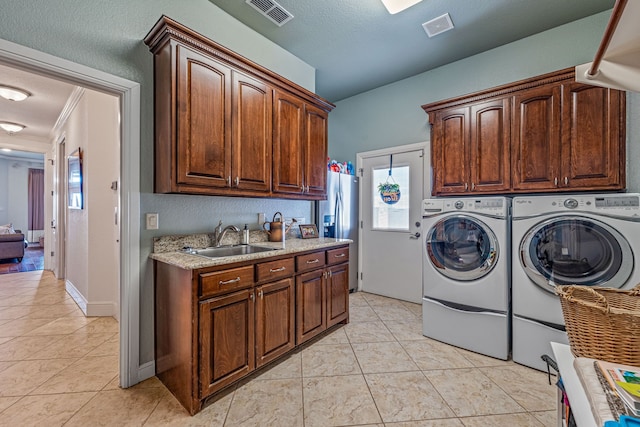 laundry area with sink, light tile patterned floors, cabinets, independent washer and dryer, and a textured ceiling