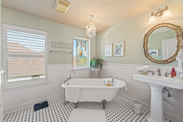 bathroom with a washtub and a notable chandelier