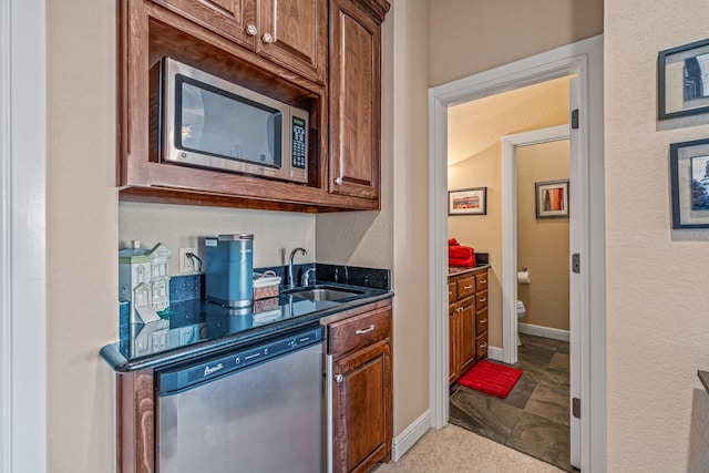 kitchen with sink, stainless steel appliances, and dark stone counters