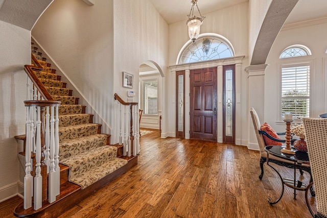 foyer with a high ceiling, crown molding, hardwood / wood-style floors, and a notable chandelier