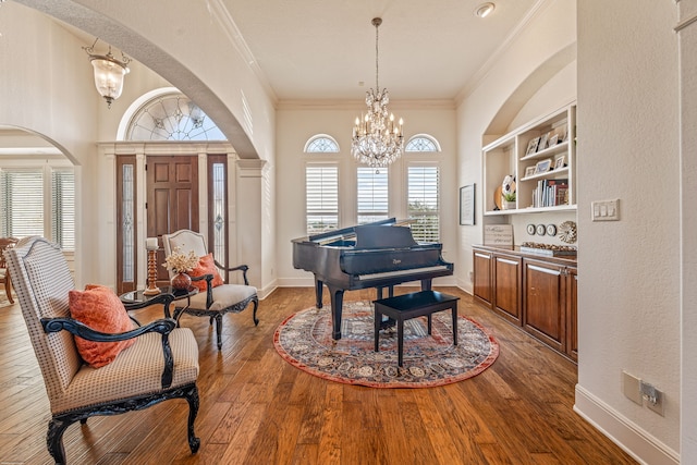 miscellaneous room featuring an inviting chandelier, wood-type flooring, crown molding, and built in features