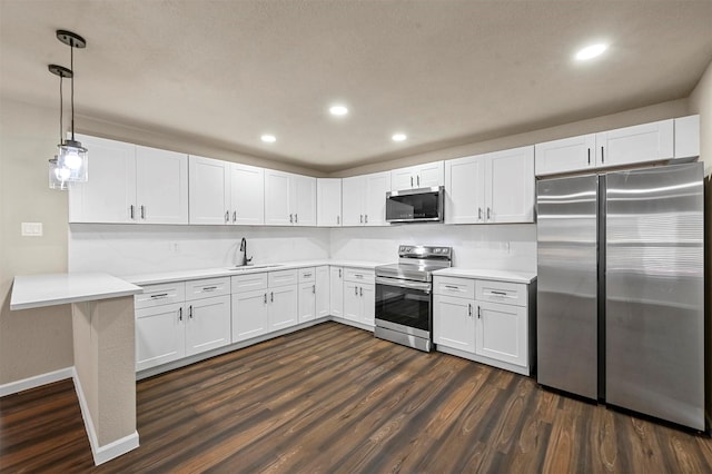 kitchen with pendant lighting, sink, appliances with stainless steel finishes, white cabinetry, and dark hardwood / wood-style floors