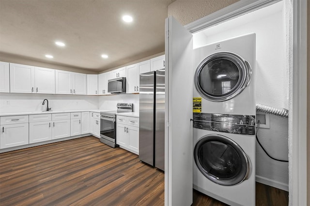 clothes washing area with stacked washer and dryer, dark wood-type flooring, and sink