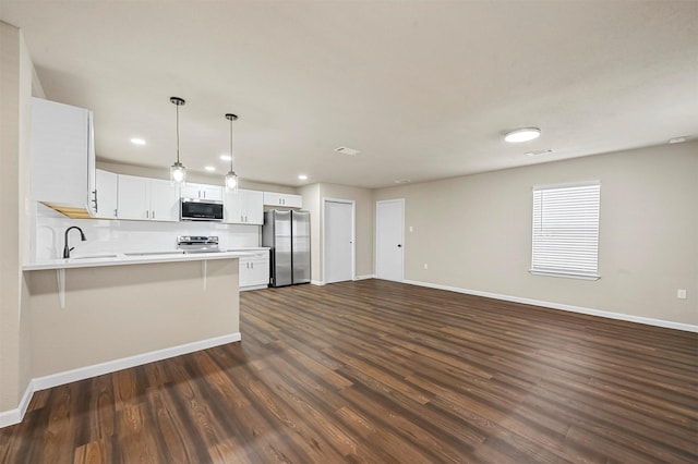 kitchen with pendant lighting, stainless steel appliances, white cabinets, dark hardwood / wood-style flooring, and kitchen peninsula