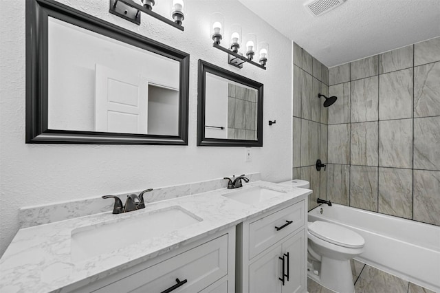 full bathroom featuring vanity, toilet, tiled shower / bath combo, and a textured ceiling