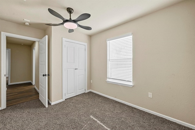 unfurnished bedroom featuring dark colored carpet, ceiling fan, and a closet