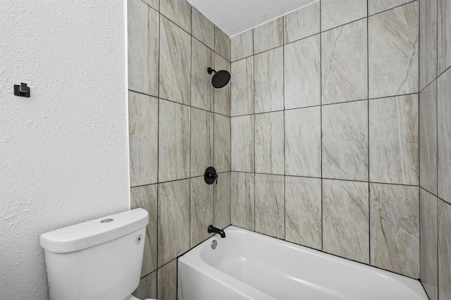 bathroom with tiled shower / bath, toilet, and a textured ceiling