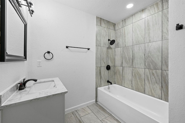 bathroom featuring tiled shower / bath, vanity, and a textured ceiling