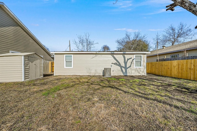 rear view of house featuring central AC, a shed, and a lawn