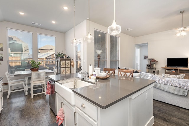 kitchen with dark hardwood / wood-style flooring, a kitchen island with sink, hanging light fixtures, and white cabinets