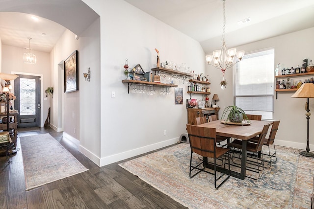 dining room with lofted ceiling, dark hardwood / wood-style floors, and a notable chandelier