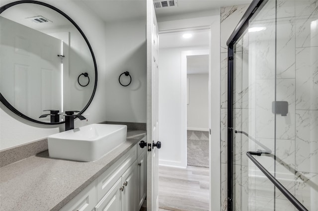 bathroom featuring a marble finish shower, vanity, and visible vents