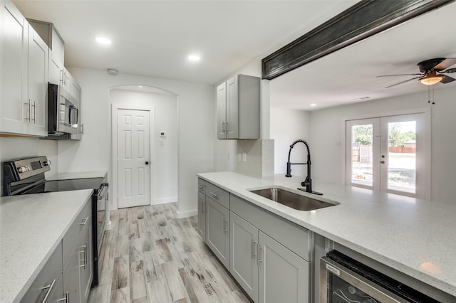 kitchen with sink, gray cabinetry, beverage cooler, stainless steel appliances, and light hardwood / wood-style flooring