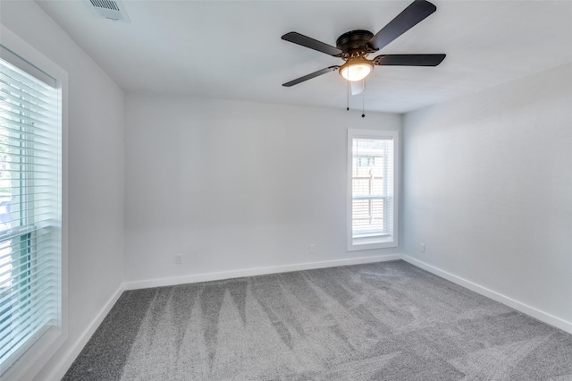 empty room featuring a ceiling fan, carpet, visible vents, and baseboards