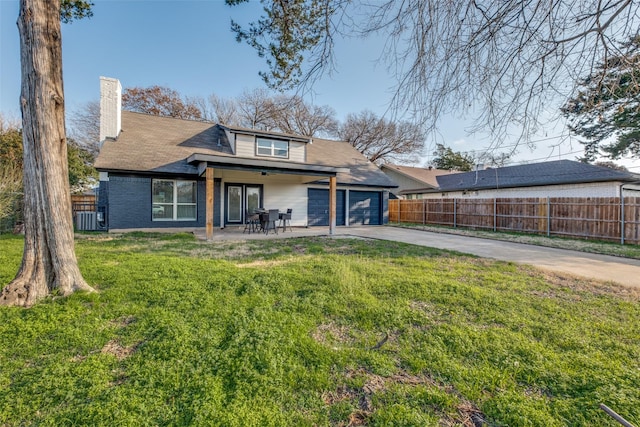 rear view of property featuring driveway, brick siding, fence, and a yard