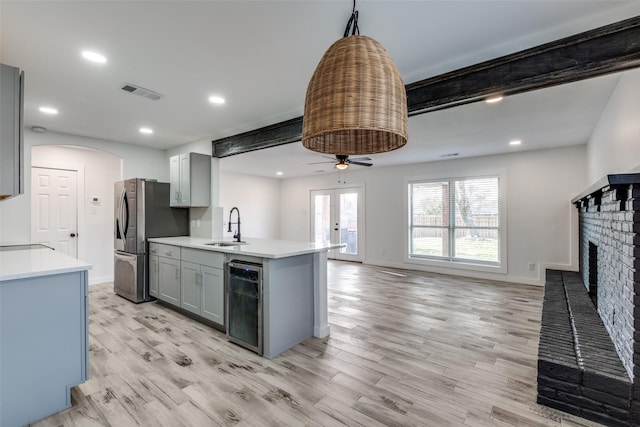 kitchen with visible vents, light countertops, gray cabinetry, stainless steel refrigerator with ice dispenser, and a sink