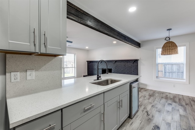 kitchen featuring sink, gray cabinetry, light stone counters, tasteful backsplash, and pendant lighting