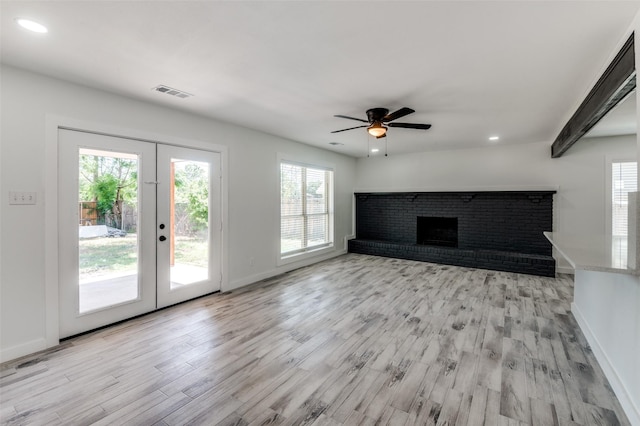 unfurnished living room featuring french doors, ceiling fan, light hardwood / wood-style floors, and a brick fireplace