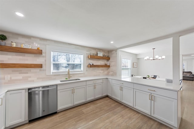 kitchen featuring dishwasher, sink, pendant lighting, and white cabinets