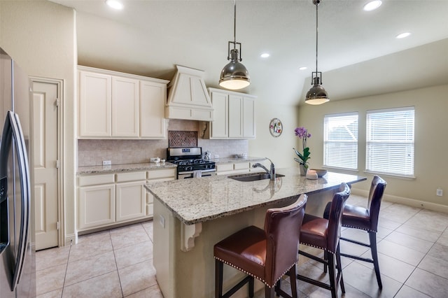 kitchen featuring pendant lighting, an island with sink, white cabinetry, sink, and stainless steel appliances