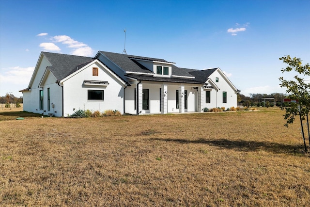 rear view of house featuring covered porch and a lawn