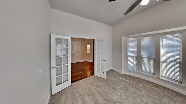 carpeted spare room with vaulted ceiling, french doors, and ceiling fan