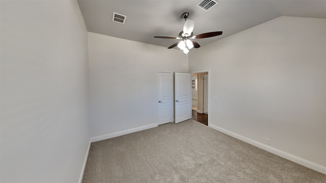 carpeted spare room featuring vaulted ceiling and ceiling fan